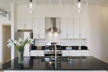 A modern kitchen with a black countertop and white cabinets.